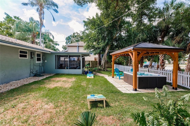 view of yard with a sunroom, a hot tub, and a gazebo