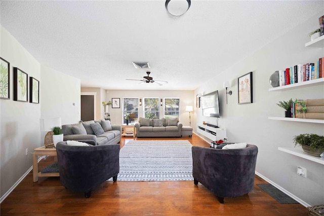 living room with ceiling fan, dark hardwood / wood-style floors, and a textured ceiling