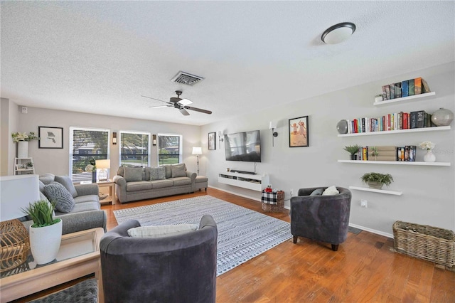 living room featuring ceiling fan, hardwood / wood-style flooring, and a textured ceiling