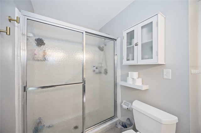 bathroom featuring toilet and a shower with shower door