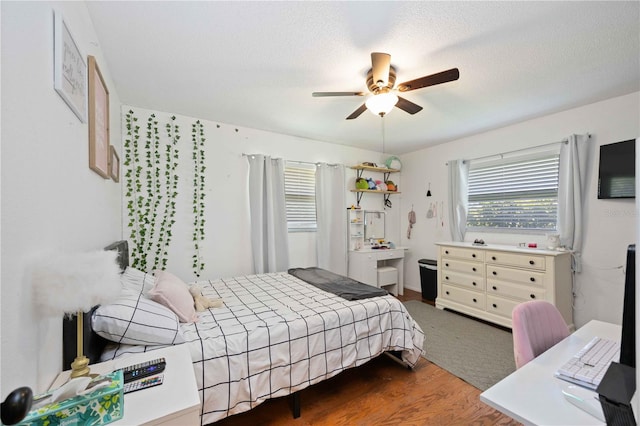 bedroom featuring dark wood-type flooring, ceiling fan, and a textured ceiling