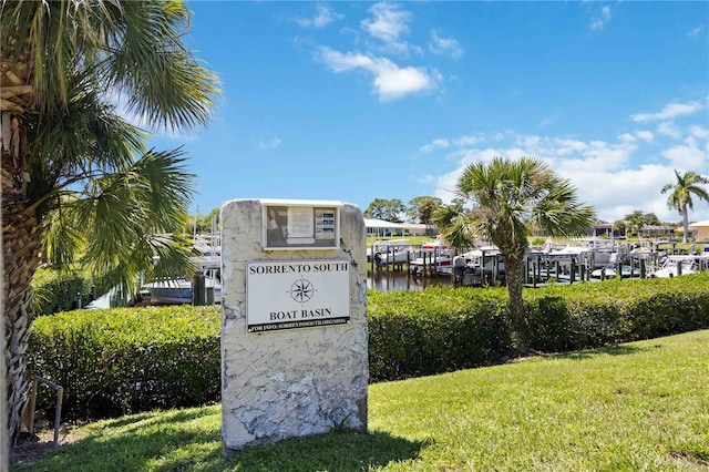 community sign with a water view and a lawn