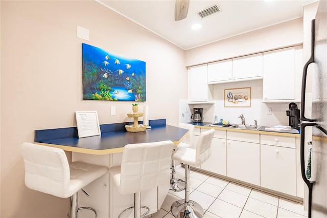 kitchen with sink, refrigerator, white cabinetry, and backsplash