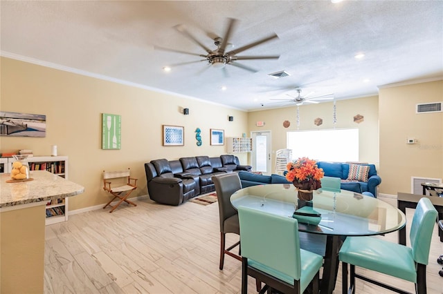 dining area with ornamental molding, light hardwood / wood-style flooring, a textured ceiling, and ceiling fan