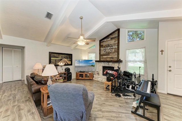 living room with lofted ceiling with beams, ceiling fan, a fireplace, and light hardwood / wood-style flooring