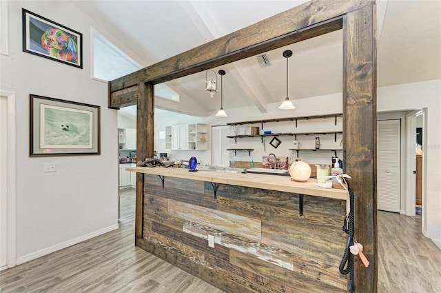 kitchen featuring decorative light fixtures, lofted ceiling with beams, wood counters, and light hardwood / wood-style flooring