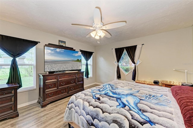 bedroom featuring a textured ceiling, light wood-type flooring, and ceiling fan