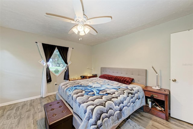 bedroom featuring ceiling fan, light hardwood / wood-style flooring, and a textured ceiling