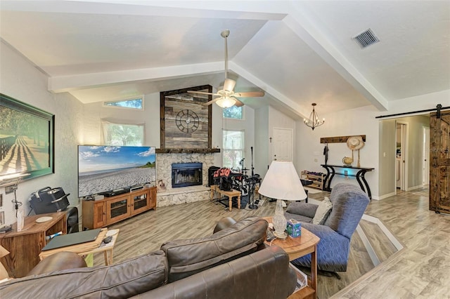 living room with vaulted ceiling with beams, ceiling fan with notable chandelier, light hardwood / wood-style flooring, and a stone fireplace