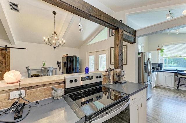 kitchen with white cabinets, lofted ceiling with beams, hanging light fixtures, a barn door, and stainless steel appliances