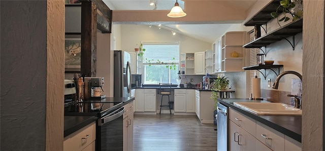 kitchen with sink, dark hardwood / wood-style floors, decorative light fixtures, vaulted ceiling, and appliances with stainless steel finishes