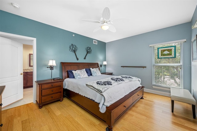 bedroom with light hardwood / wood-style flooring, ceiling fan, and ensuite bath