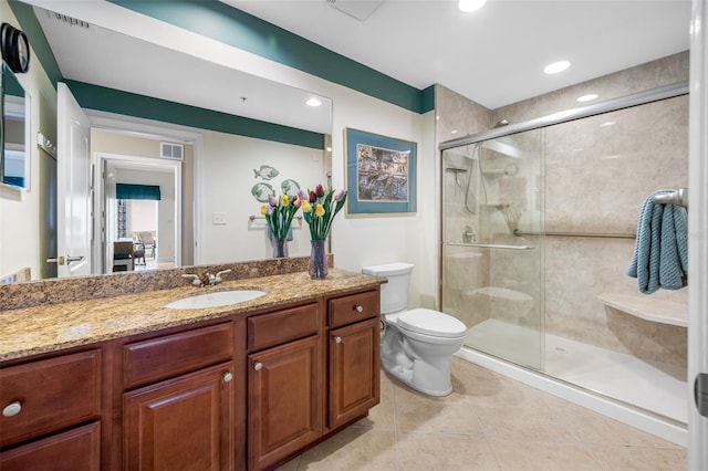 bathroom featuring tile patterned flooring, toilet, a shower with door, and vanity