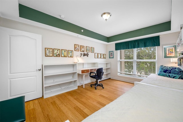 bedroom featuring built in desk and light hardwood / wood-style floors