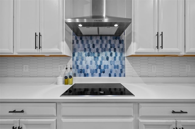 kitchen featuring tasteful backsplash, wall chimney exhaust hood, white cabinetry, and black electric cooktop