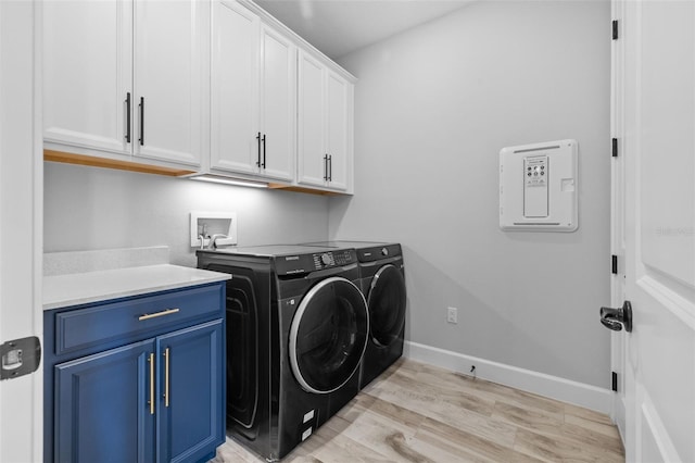 laundry area featuring light wood-type flooring, cabinets, and washing machine and dryer