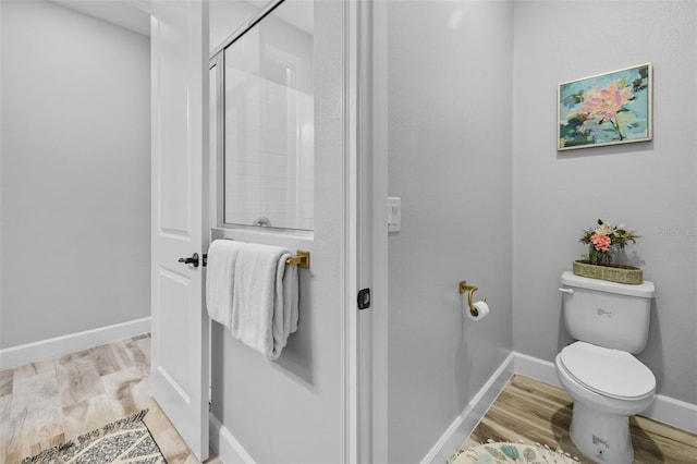 bathroom featuring toilet, wood-type flooring, and a shower with door