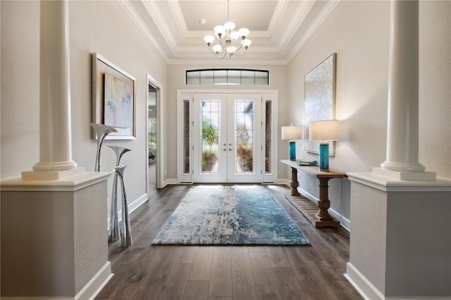 entrance foyer with dark hardwood / wood-style floors, a chandelier, a tray ceiling, and ornate columns