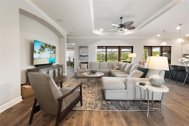 living room featuring a tray ceiling, ornamental molding, ceiling fan, and dark hardwood / wood-style floors