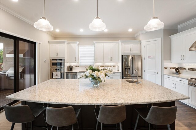 kitchen with a spacious island, hanging light fixtures, appliances with stainless steel finishes, and white cabinetry