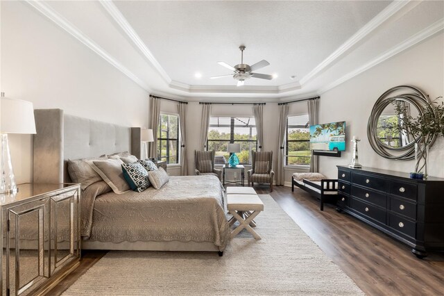 bedroom with crown molding, dark hardwood / wood-style flooring, ceiling fan, and a tray ceiling