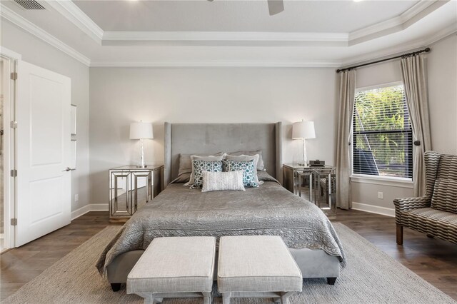 bedroom with dark wood-type flooring, a tray ceiling, ceiling fan, and crown molding