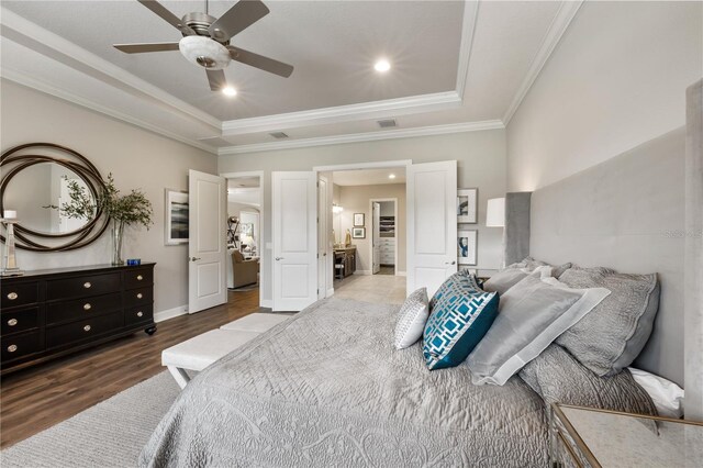 bedroom with a tray ceiling, crown molding, hardwood / wood-style floors, and ceiling fan