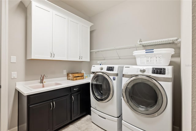 laundry area with light tile patterned floors, cabinets, washing machine and clothes dryer, and sink