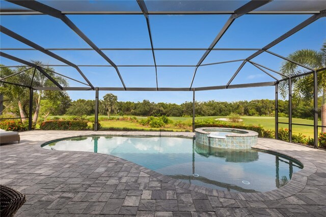 view of pool featuring glass enclosure, an in ground hot tub, and a patio area