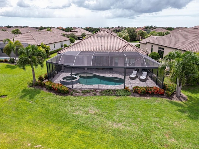 view of pool with glass enclosure, a patio area, a lawn, and an in ground hot tub