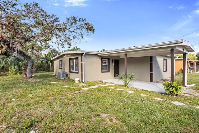 rear view of property with central AC unit and a lawn