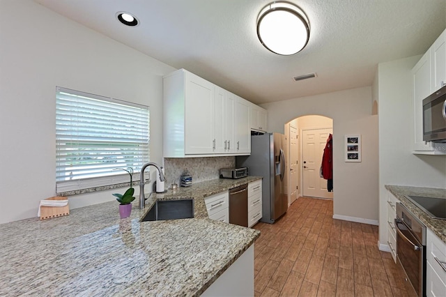 kitchen featuring light stone counters, stainless steel appliances, white cabinetry, and light hardwood / wood-style flooring