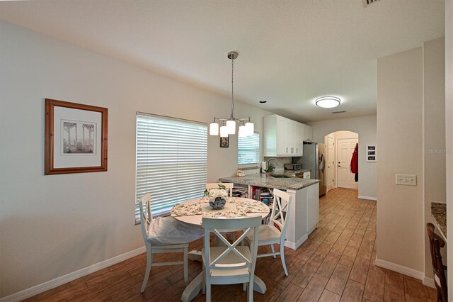 dining space featuring a chandelier, sink, and light hardwood / wood-style flooring