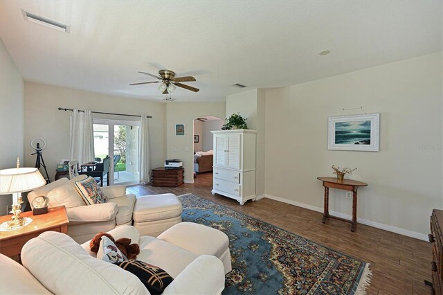 living room with dark hardwood / wood-style flooring and ceiling fan