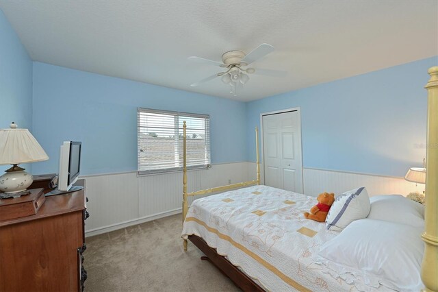 carpeted bedroom with a closet, ceiling fan, and a textured ceiling