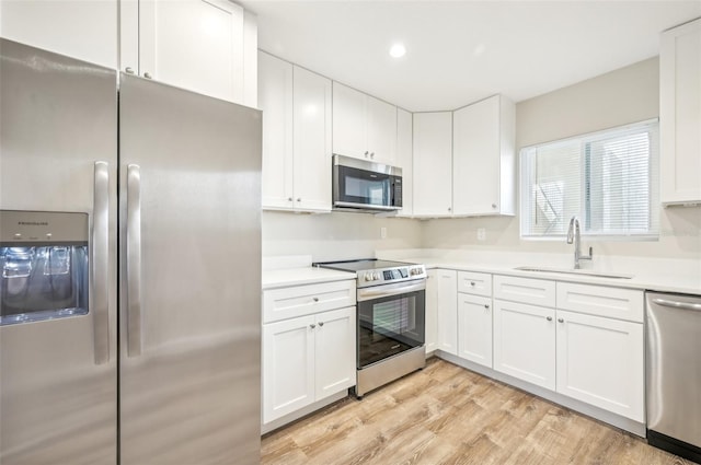 kitchen featuring light wood-type flooring, appliances with stainless steel finishes, sink, and white cabinets