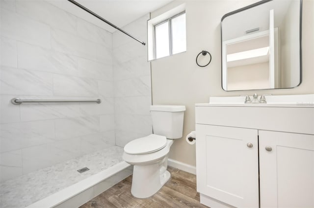 bathroom with tiled shower, vanity, toilet, and hardwood / wood-style floors