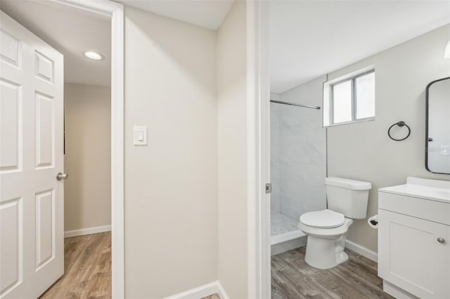 bathroom with tiled shower, vanity, toilet, and hardwood / wood-style flooring