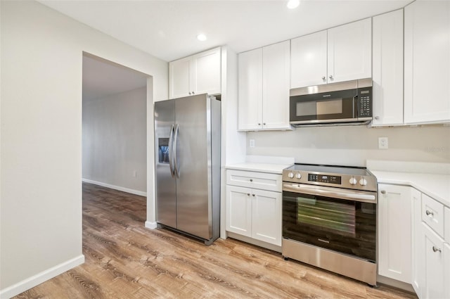 kitchen with white cabinets, stainless steel appliances, and light hardwood / wood-style floors