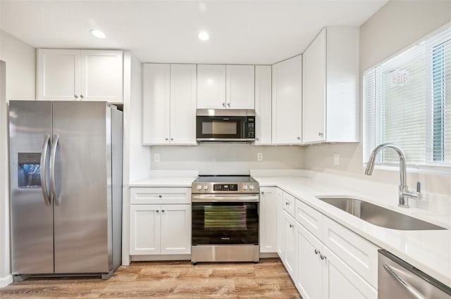 kitchen featuring white cabinets, stainless steel appliances, sink, and light hardwood / wood-style flooring