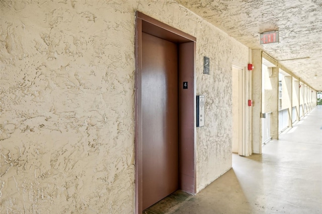 corridor featuring concrete floors and elevator