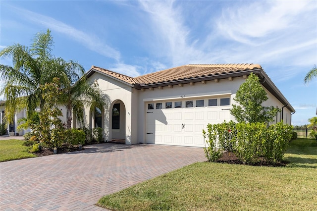 mediterranean / spanish house featuring a garage and a front lawn