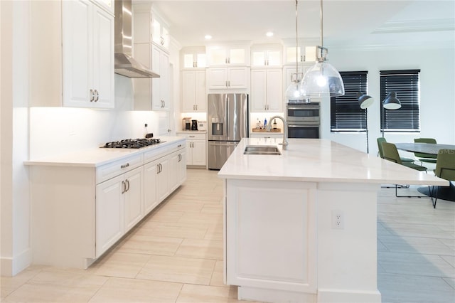 kitchen featuring appliances with stainless steel finishes, sink, white cabinets, and wall chimney range hood