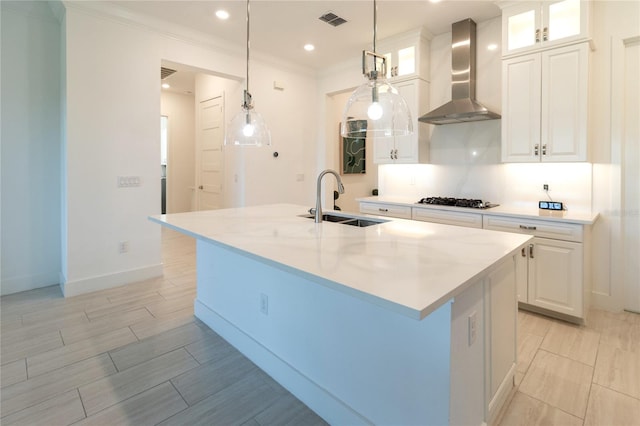 kitchen with a kitchen island with sink, wall chimney exhaust hood, sink, and white cabinets