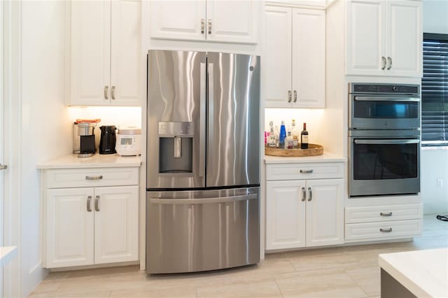 kitchen with light tile patterned floors, white cabinetry, and stainless steel appliances