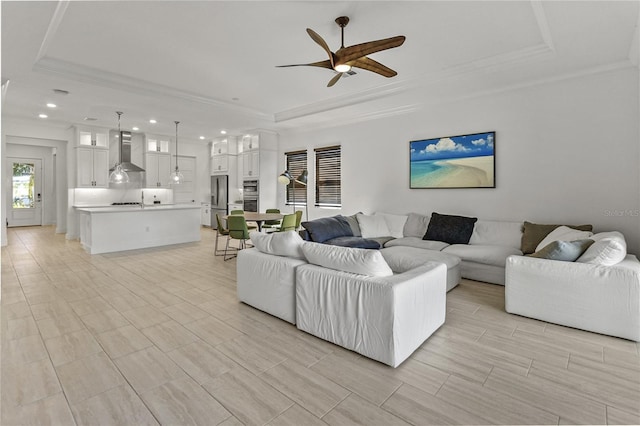 living room with crown molding, a raised ceiling, and ceiling fan