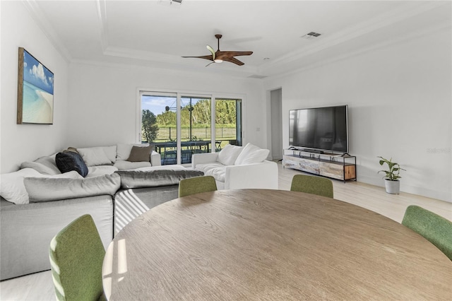 living room with crown molding, a raised ceiling, ceiling fan, and light hardwood / wood-style floors