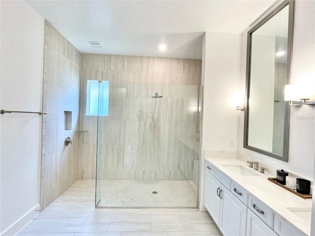 bathroom with tiled shower and vanity