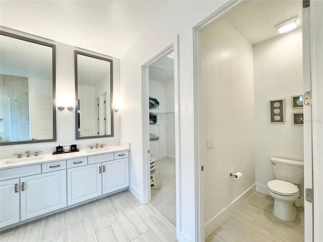 bathroom with toilet, a textured ceiling, and vanity