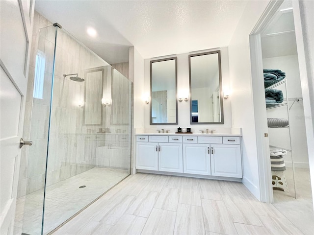 bathroom with vanity, a textured ceiling, and a tile shower